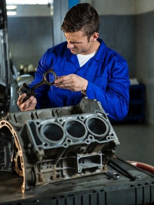 Mechanic inspecting engine block components in auto repair shop, emphasizing engine diagnostics and maintenance services at Route 40 Auto.