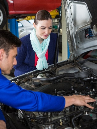 Mechanic inspecting engine with customer observing, highlighting expert engine diagnostics and maintenance services at Route 40 Auto.