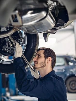 Auto mechanic inspecting vehicle components under a car, emphasizing reliable auto repairs and maintenance services at Route 40 Auto.