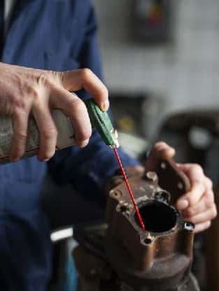 Mechanic applying lubricant to an exhaust component, emphasizing exhaust and muffler repair services at Route 40 Auto.