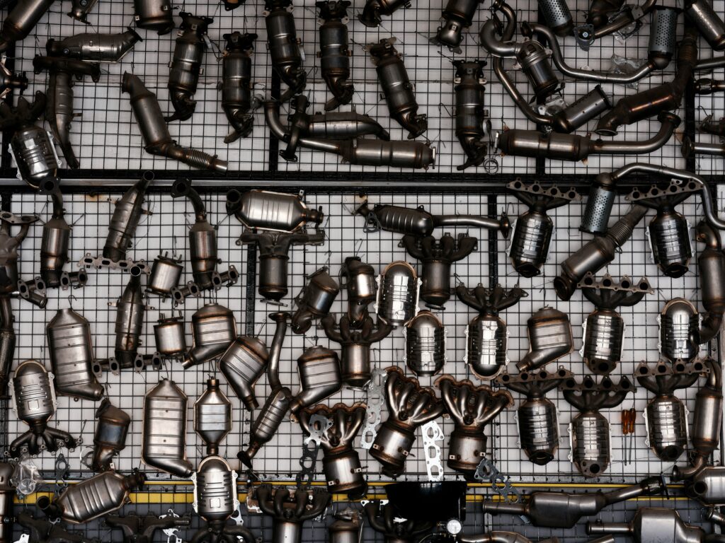 Various catalytic converters and exhaust components displayed on a grid, relevant to automotive repair and catalytic converter replacement.